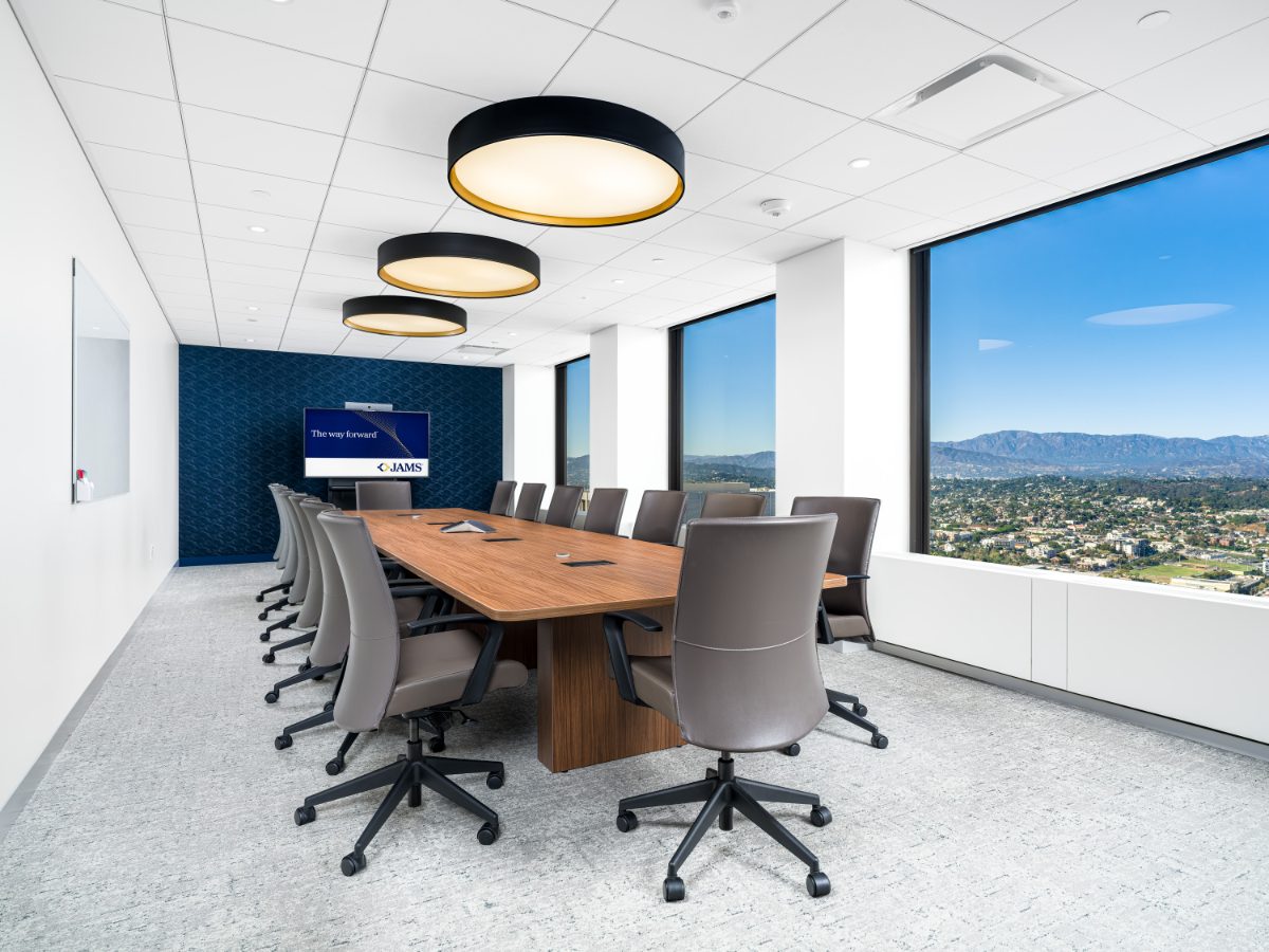 JAMS Los Angeles boardroom at City National Plaza — walnut conference table, charcoal leather chairs, black drum pendants, navy accent wall, mountain skyline view.