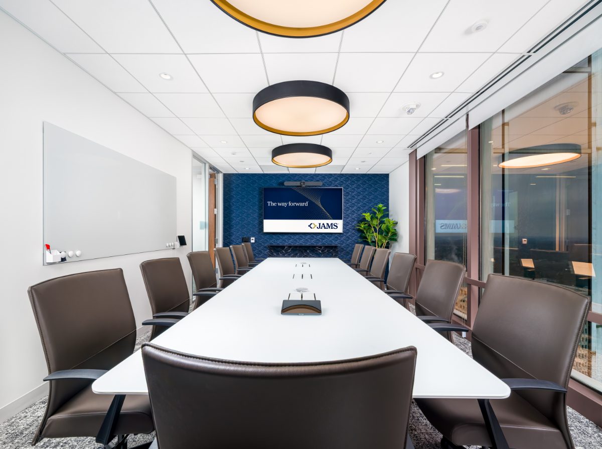JAMS Atlanta Board Room 02 at Promenade Tower — long white table, brown leather chairs, three drum pendants in perspective, navy patterned wall with display.