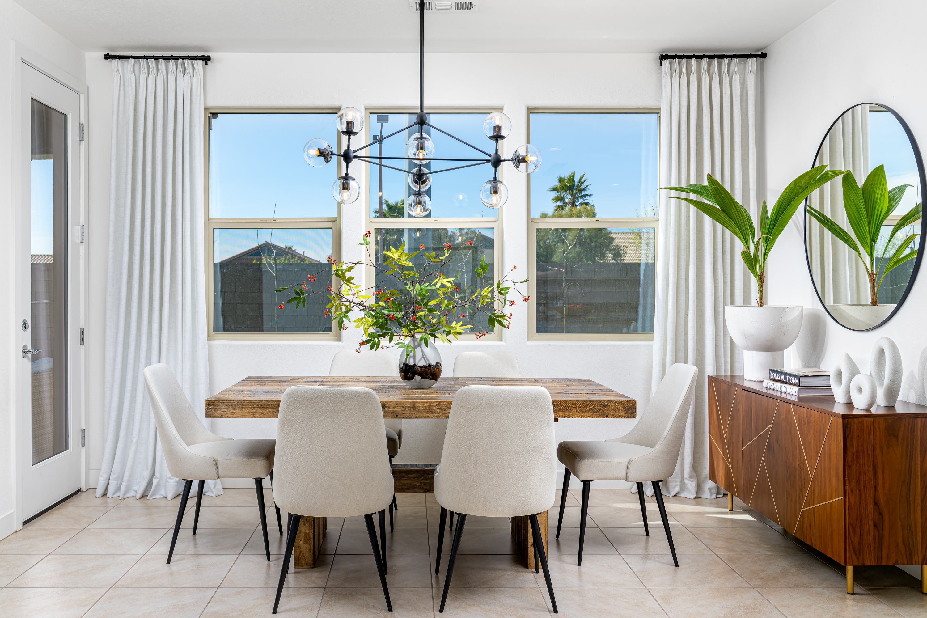 Dining Room at a Stately contemporary minimalist home in Las Vegas (11531 SSS) — reclaimed-wood pedestal table, white side chairs, black-and-glass orb chandelier, walnut sideboard.
