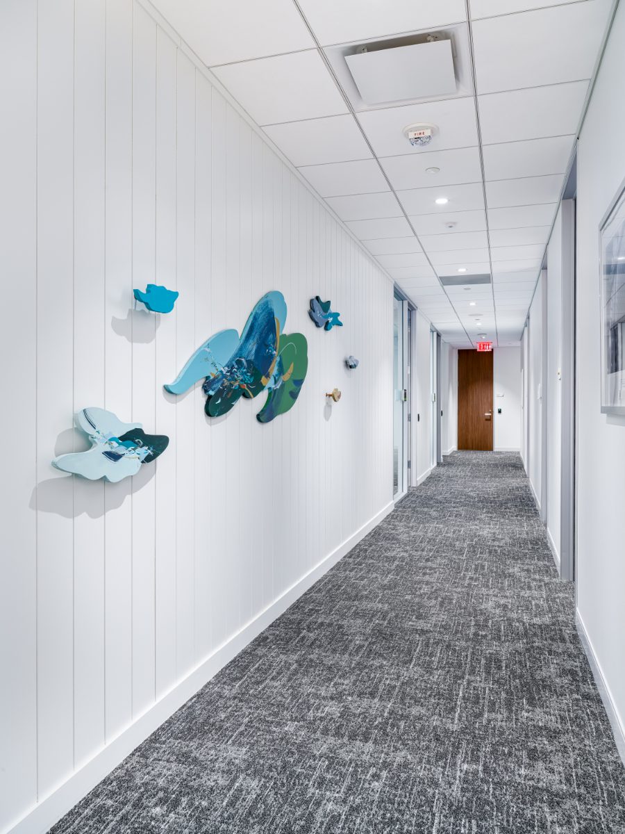 JAMS Atlanta corridor at Promenade Tower with dimensional sculptural wall art by local artists — layered blue, teal, and gold organic shapes on a white shiplap wall.
