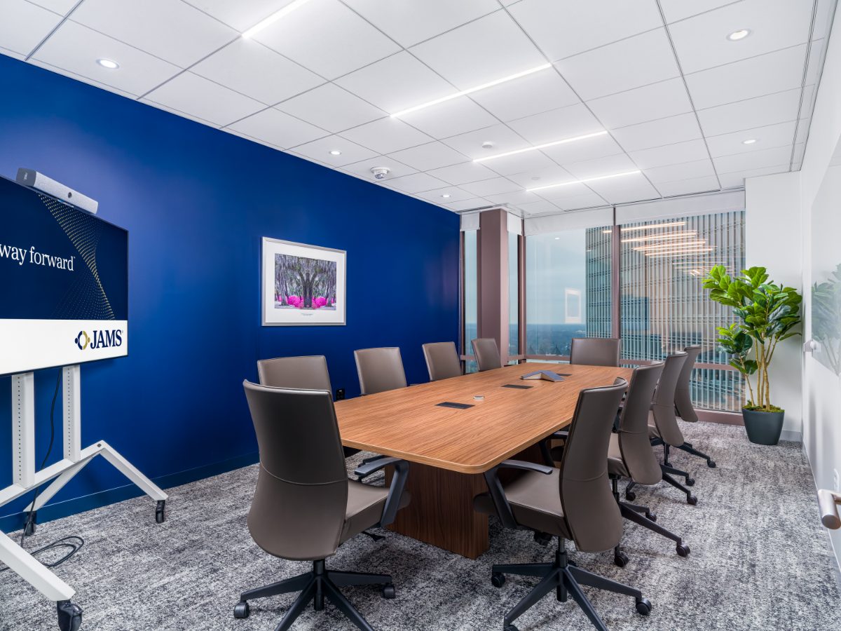 JAMS Atlanta Conference Room 14 at Promenade Tower — walnut table, brown leather chairs, cobalt wall with framed botanical art, fiddle-leaf fig in the corner.