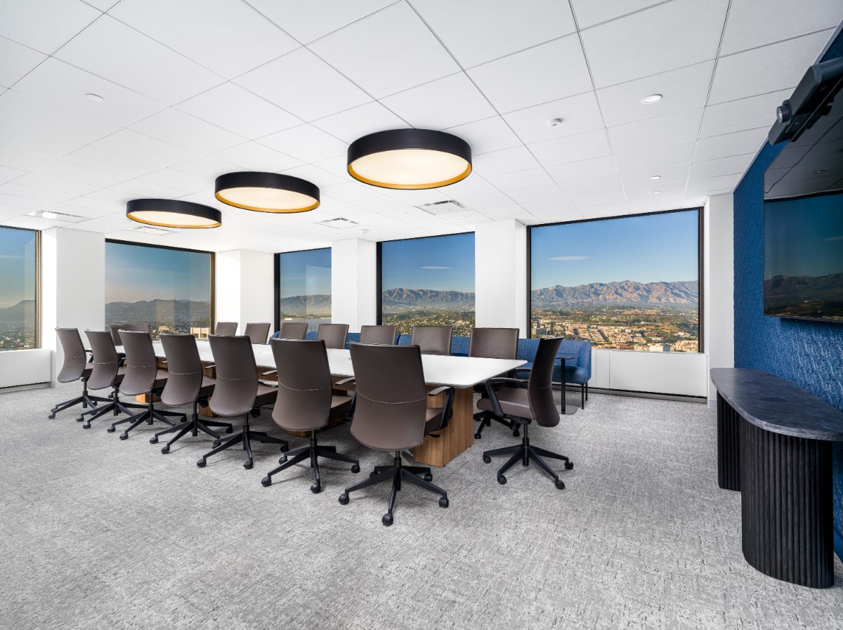 JAMS LA Conference Room 35 — long white-quartz table on walnut plinth, charcoal leather chairs, drum pendants, wraparound windows onto the San Gabriels.