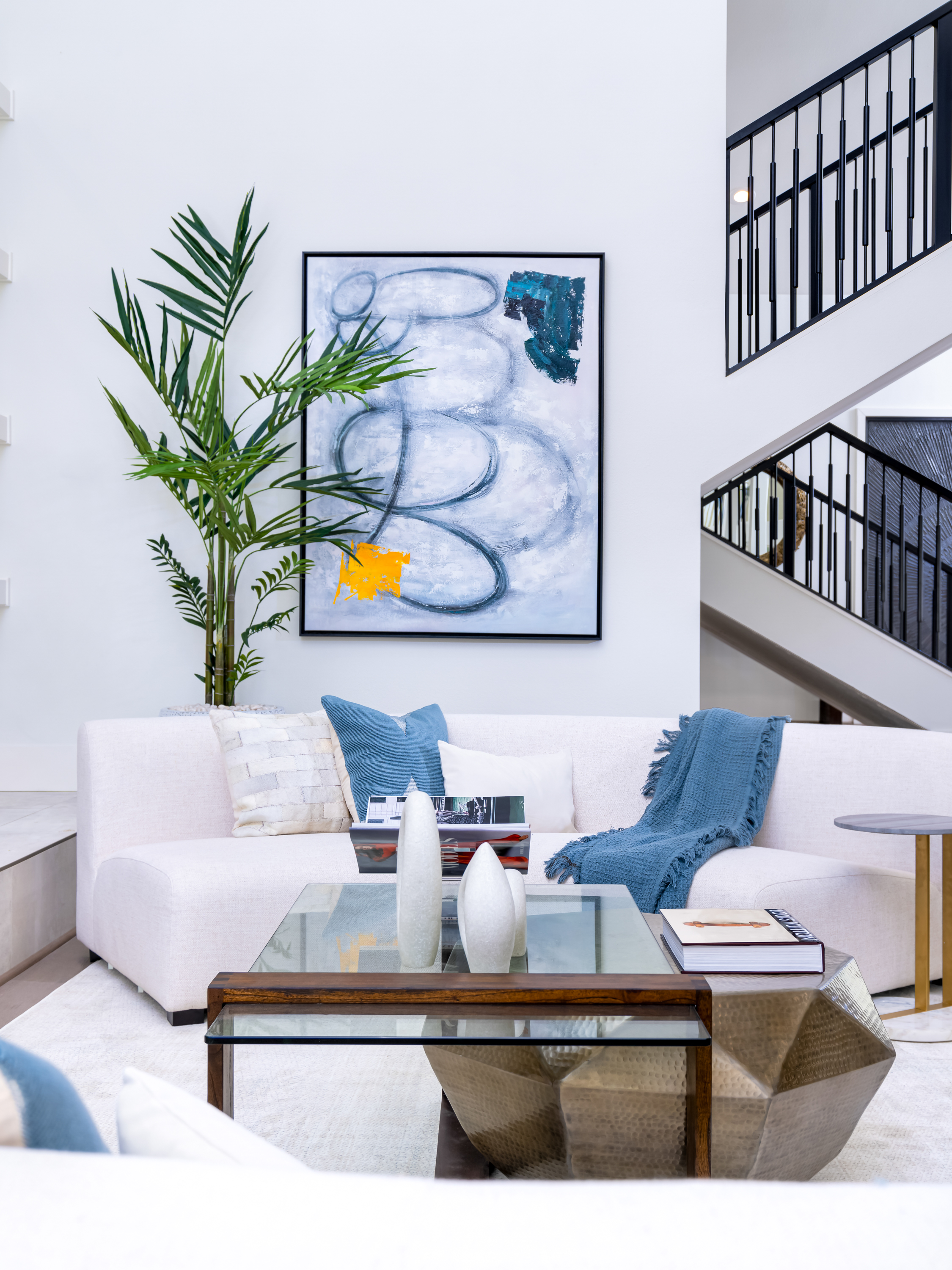 Living Room at a Stately open contemporary home in Las Vegas (2327 AD) — vaulted ceiling, central fireplace, faceted metallic coffee table, blue accent art.