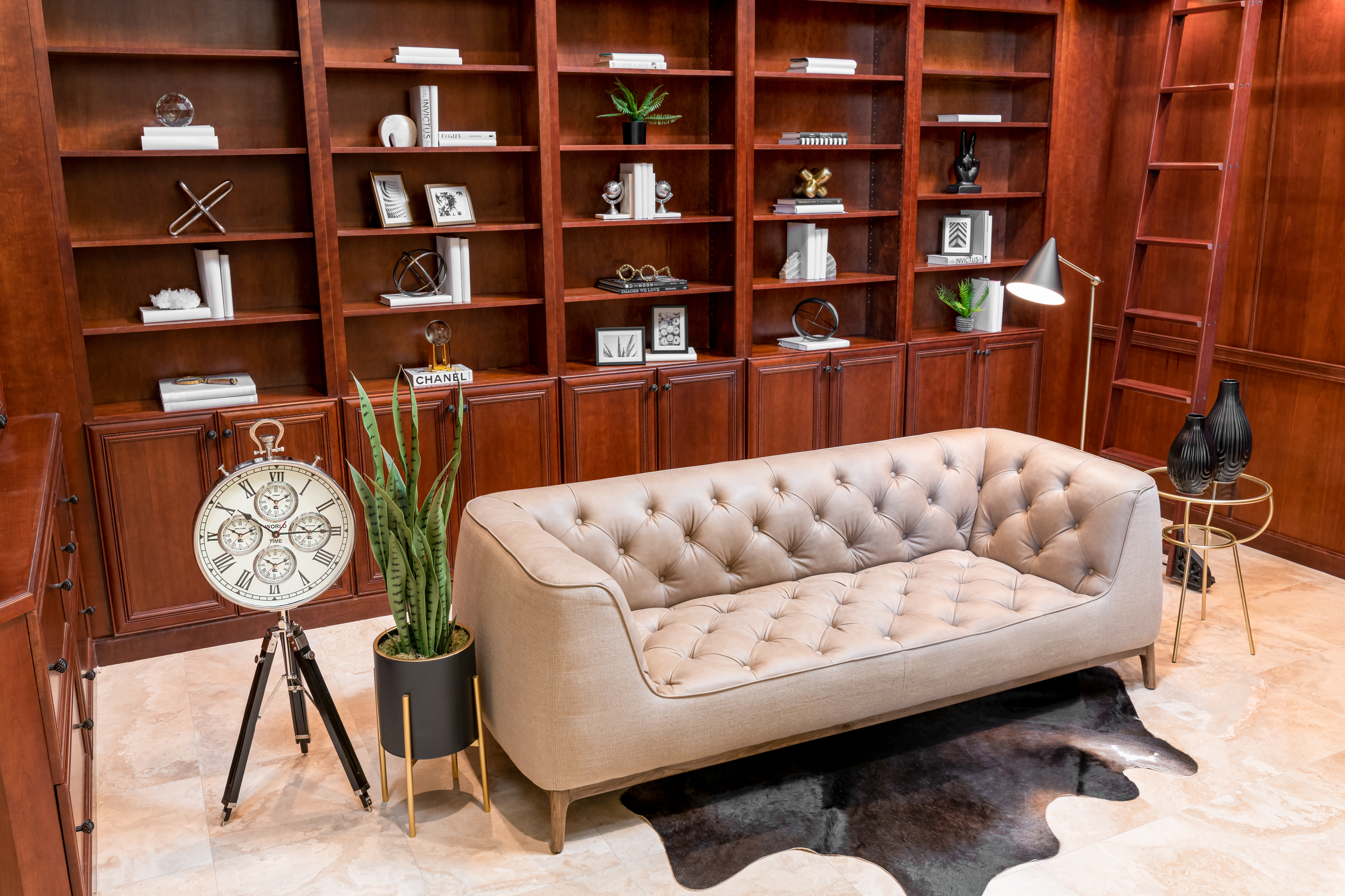 Library at a Stately traditional gentleman's library home in Las Vegas (2297 FA) — cherry bookcases, rolling library ladder, tufted cream sofa, antique tripod clock.