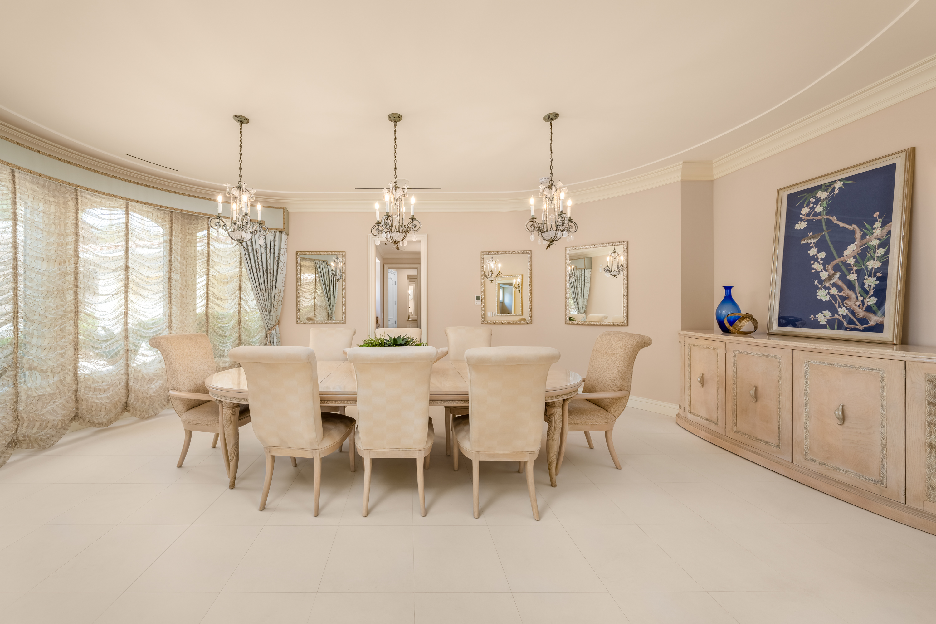 Dining Room at a Stately glam estate home in Las Vegas (5114 SHD) — two-story curtains, paired gold-base ottomans, marble fireplace, panoramic view.