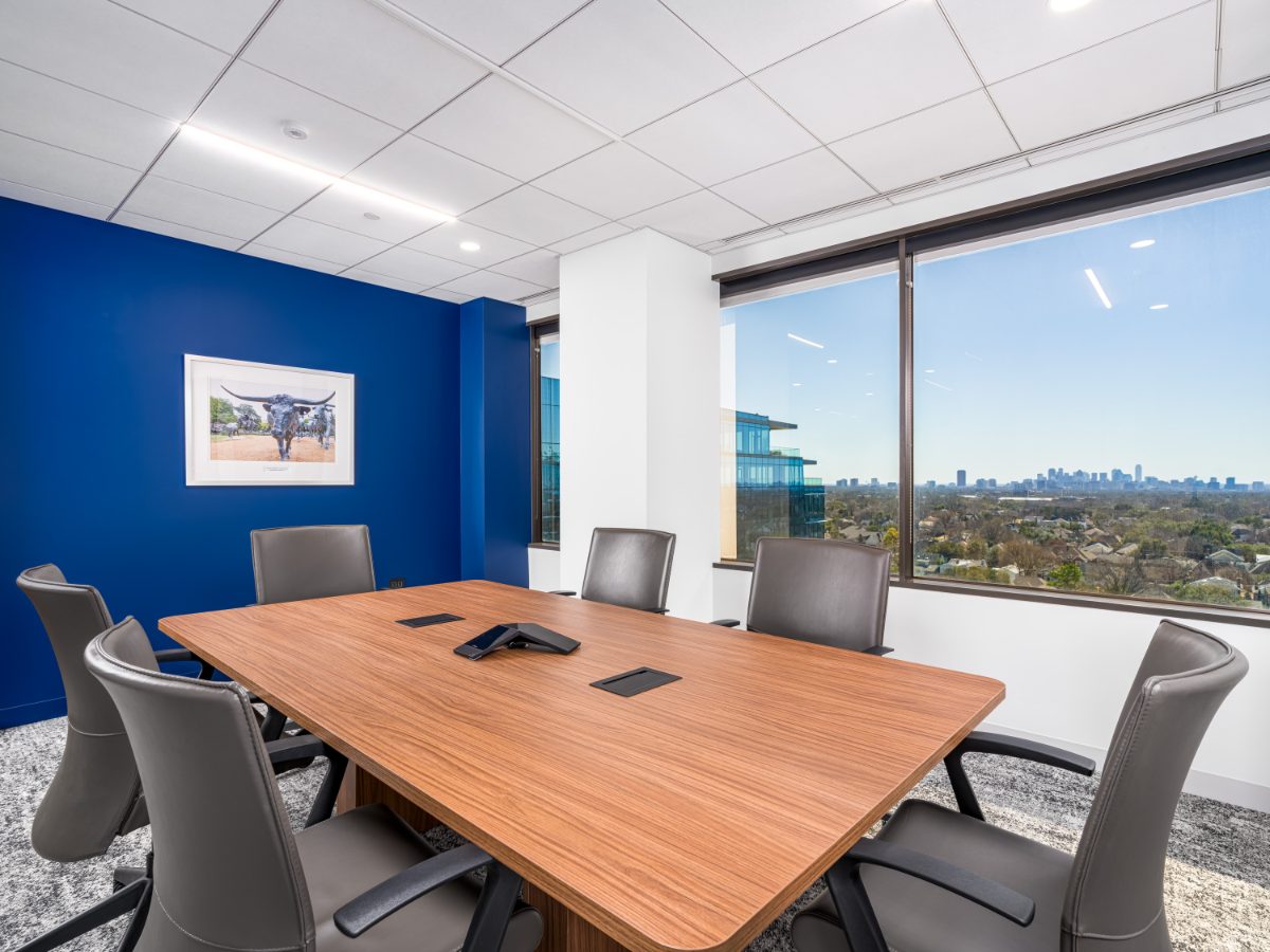 JAMS Dallas conference room at Sherry Lane Place — walnut table, grey leather chairs, cobalt accent wall, framed longhorn art, downtown Dallas skyline window.