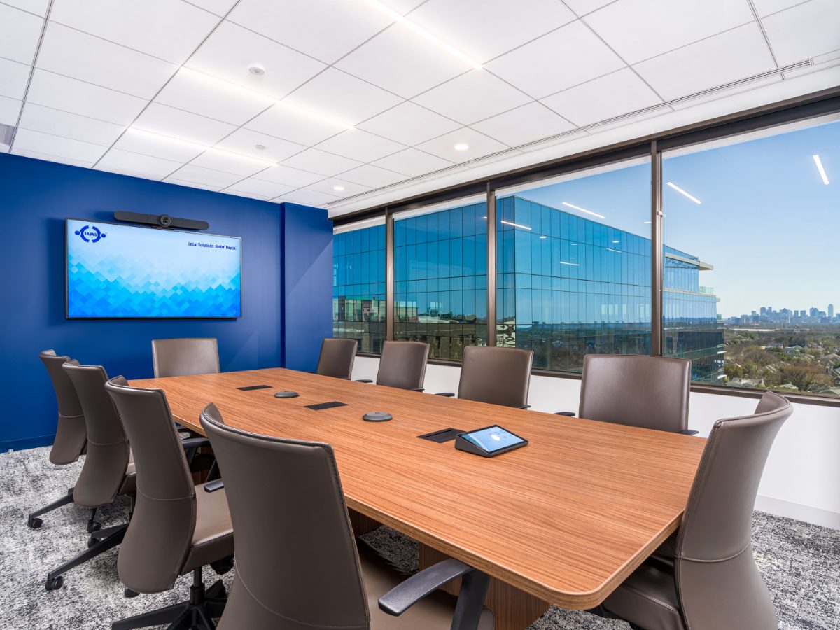 JAMS Dallas mid-size conference room at Sherry Lane Place — walnut table, grey leather chairs, cobalt wall with JAMS display screen, mirrored neighboring tower.
