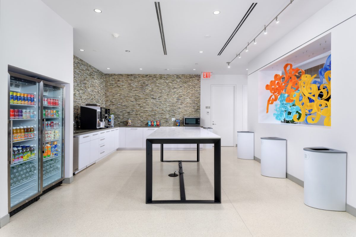 JAMS NY JAMS Café — twin beverage refrigerators, white cabinetry, stacked-stone backsplash, central high-top, back of the lounge sculpture through pass-through.