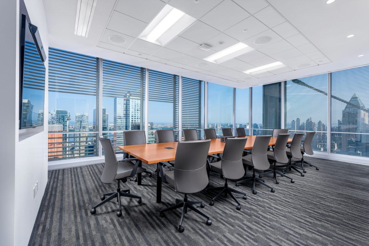 JAMS NY Conf Room 8 — long cherry table, grey leather chairs, two walls of floor-to-ceiling windows with NYT louvers framing Midtown and the Hudson River.